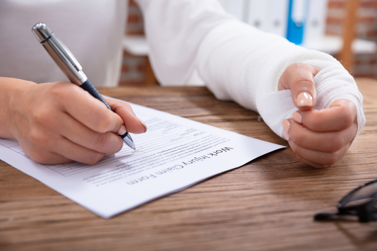 A worker who has been injured while at work is filling out the injury claim sheet for workers' compensation.